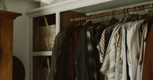 Clothing rack with shirts and jackets in a room with wooden furniture and a basket.