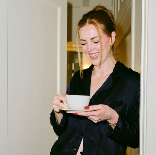 Female standing with a cup of coffee in a doorway.