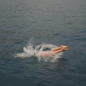 Person diving into a body of water with a splash.